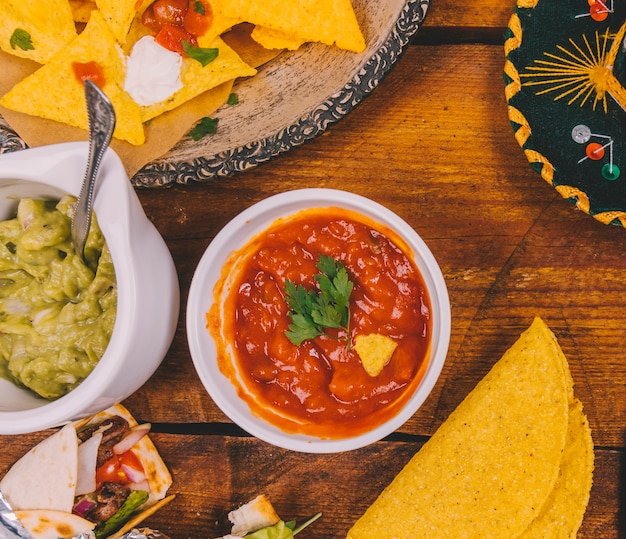 Salsa guacamole nachos tortilla wrap and tacos on wooden table from Freepik